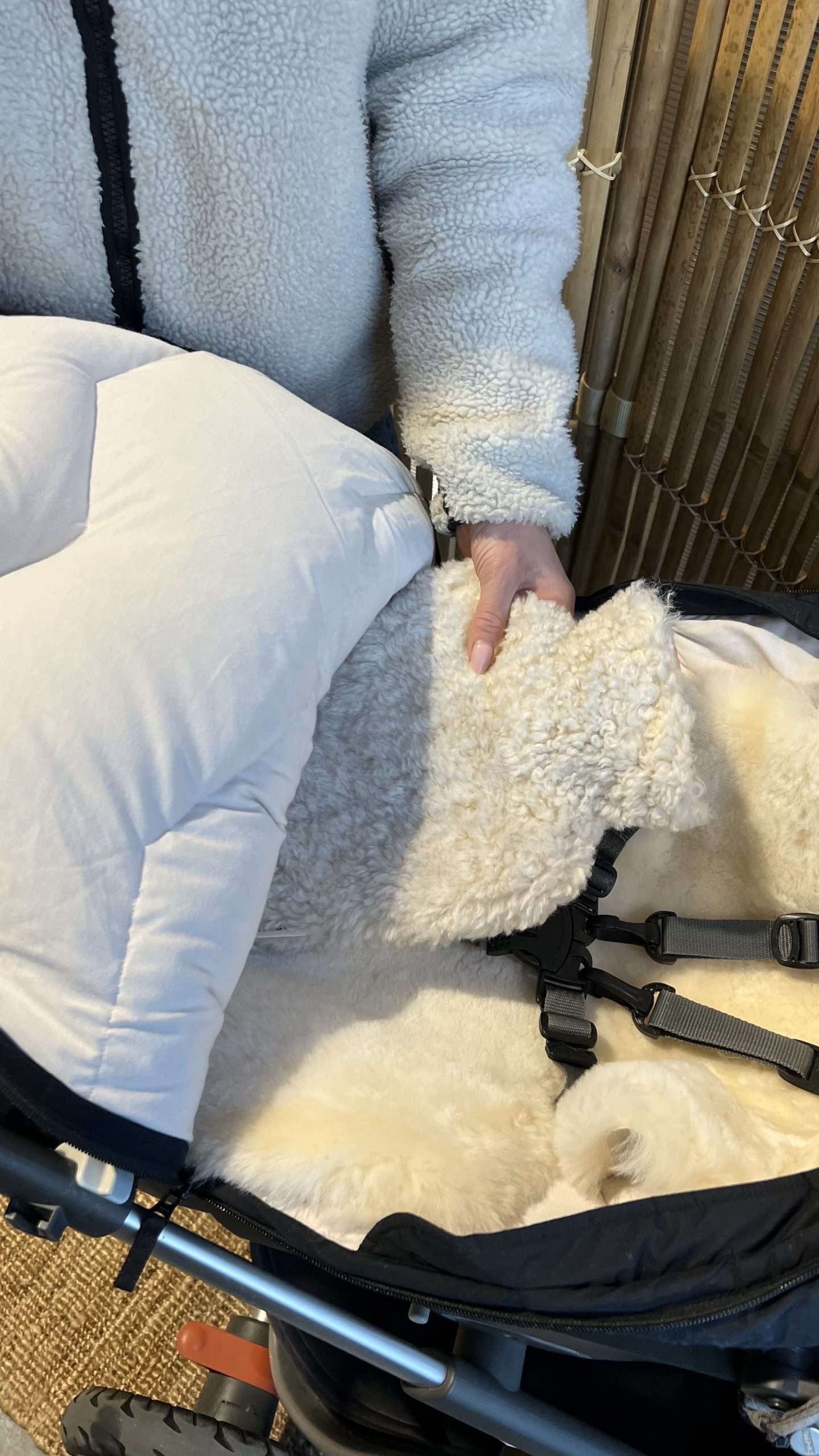 Varmeelement med trekk i ull plasseres neddi en vognpose som er i en vogn. På innsiden av vognposen er det montert et lammeskinn.