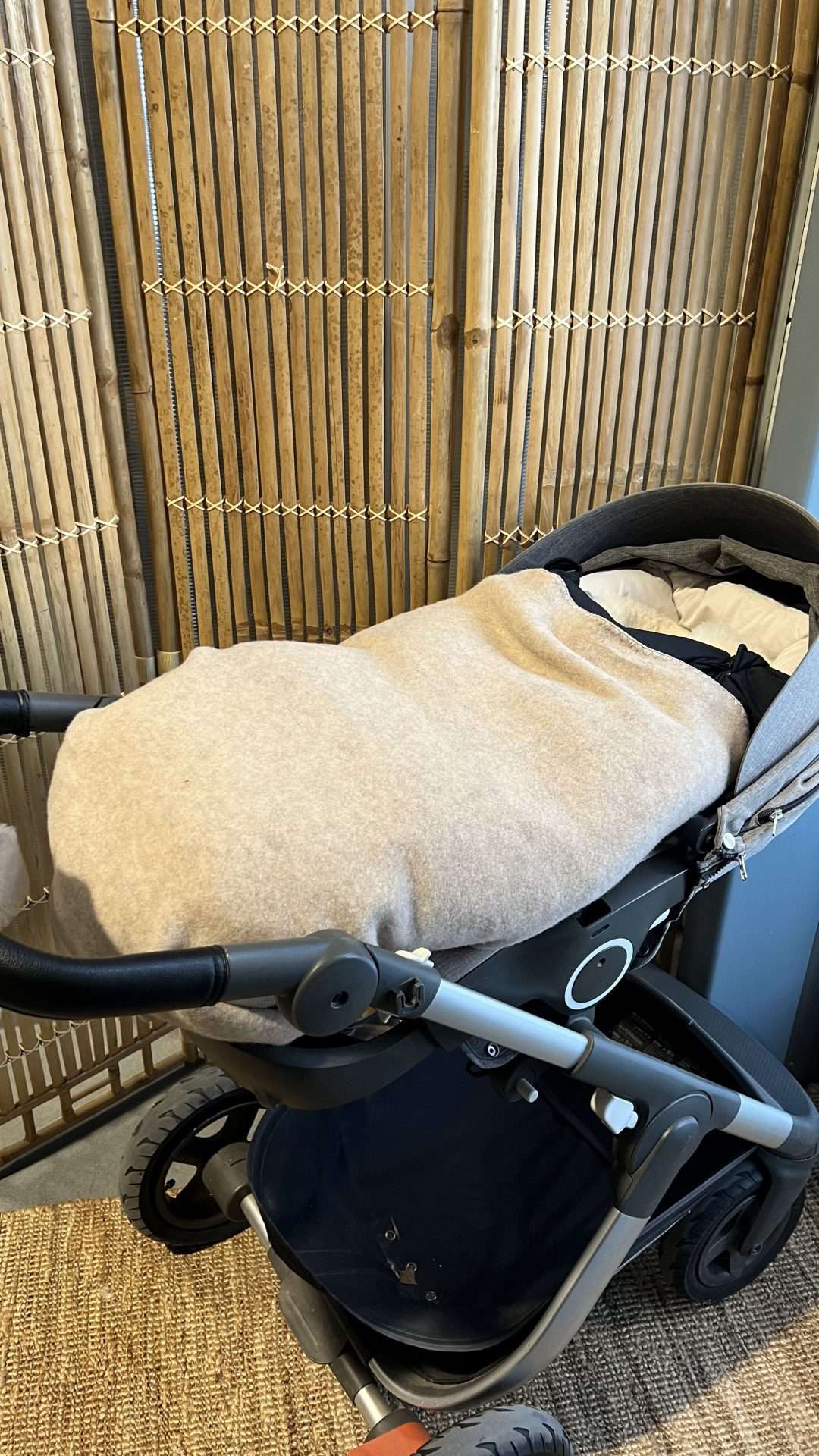 Barnevogn med vognpose og en beige ullteppe tettpakket rundt der igjen. Tips når baby skal sove i vogn i minusgrader.