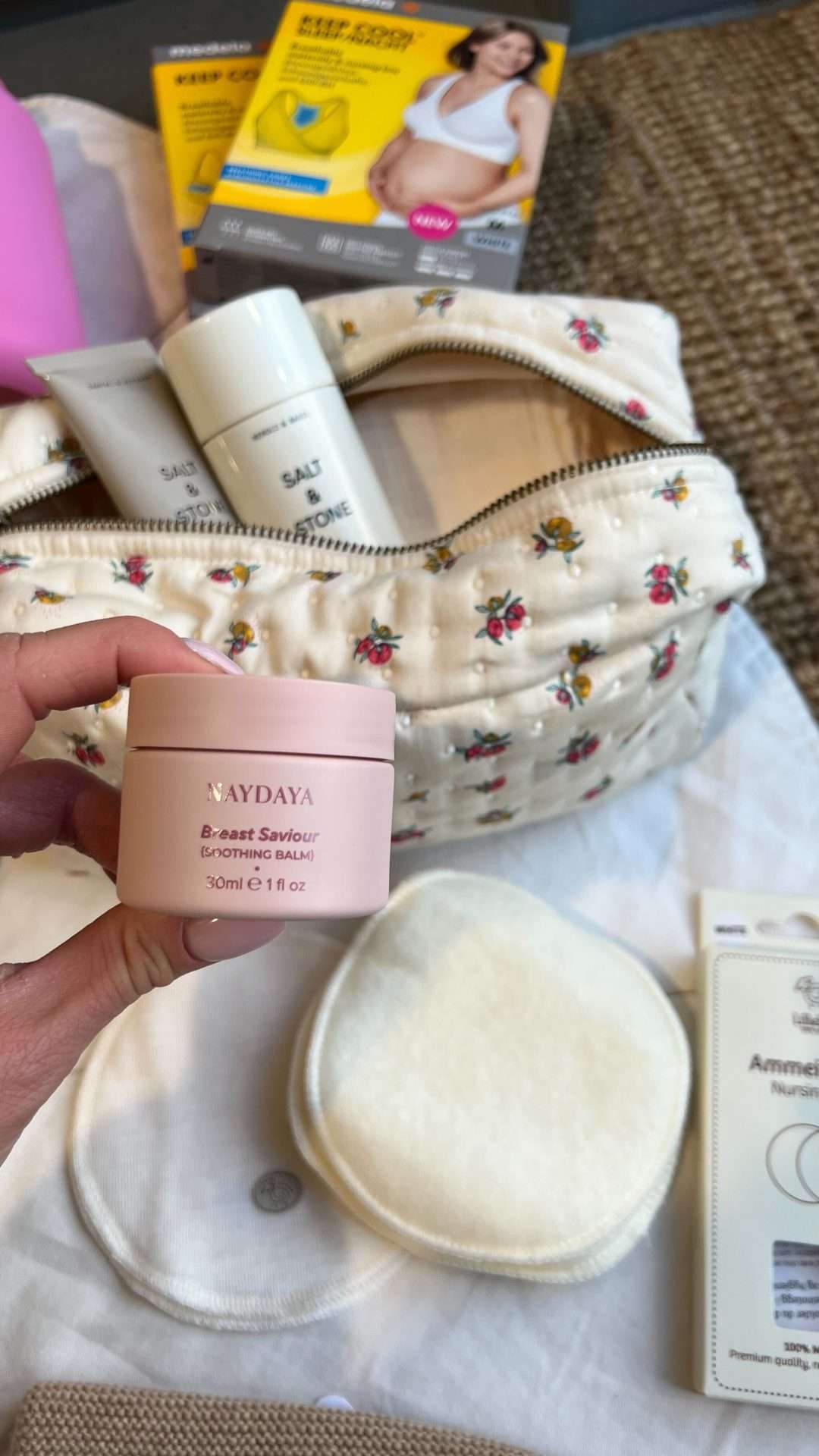 Brystvortekrem fra Naydaya. 100% naturlig. Kommer i en rosa kremboks. Fin å ha med i fødebag. I bakgrunnen synes en toalettmappe fylt med andre hygieneproduykter til fødebag, ammeinnlegg og amme bh.