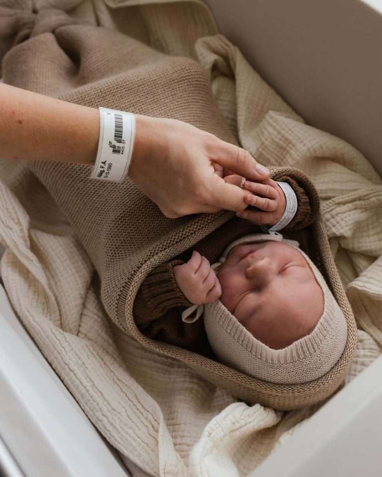 nyfodt-baby-ligger-i-svopeposen-fra-hvid-farge-sand