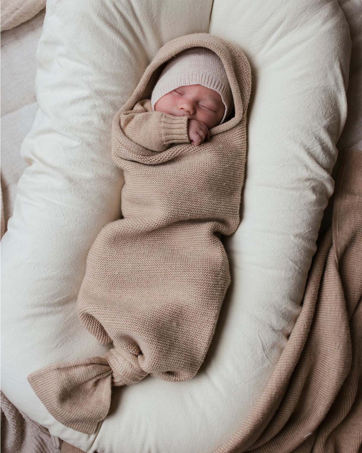 nyfødt baby ligger i svøpeposen merinoull ubehandlet ull ullklær fra hvid farge sand oppi babynest snuggle me organic